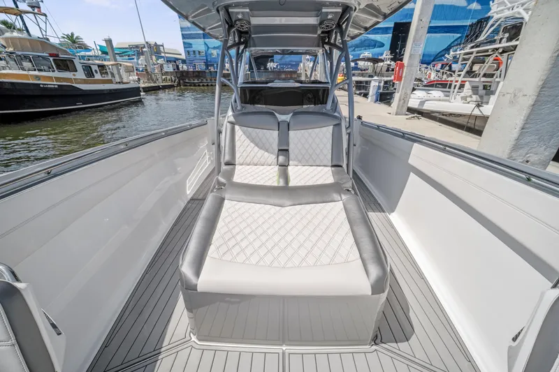 Slide: The Image of 2021 Nor-Tech 390 Sport Center Console boat interior with cushioned seating at a marina. - 28