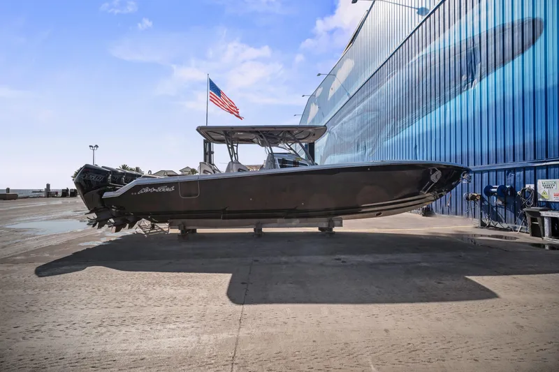 Slide: The Image of 2021 Nor-Tech 390 Sport Center Console boat with American flag, docked near blue building. - 30