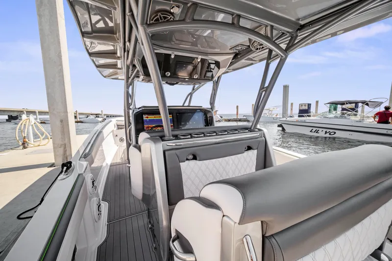 Slide: The Image of 2021 Nor-Tech 390 Sport Center Console boat interior at dock, featuring modern seating and navigation equipment. - 35