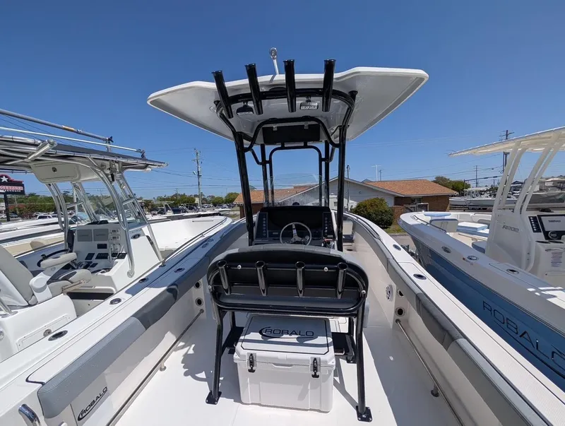 Slide: The Image of 2025 Robalo R232 Explorer boat interior with helm and seating, under clear blue sky. - 11