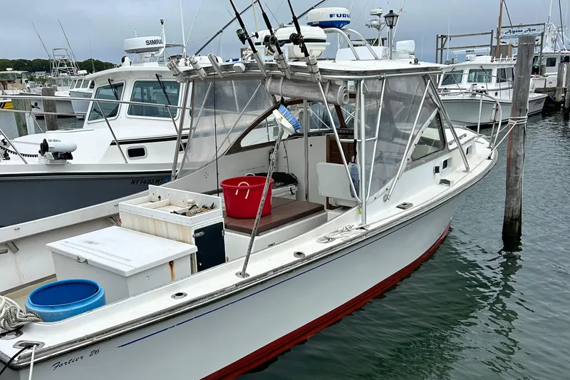 Slide: The Image of 1991 Fortier 26 Hard Top boat docked, featuring fishing equipment and storage containers. - 2