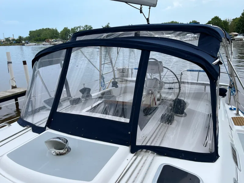 Slide: The Image of 2004 Hunter 41 sailboat with blue canopy docked on a calm lake. - 12