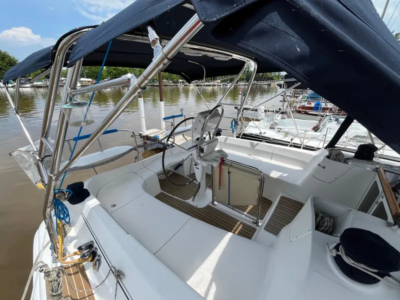 Slide: The Image of 2004 Hunter 41 sailboat cockpit with blue canopy, docked by a calm river. - 13