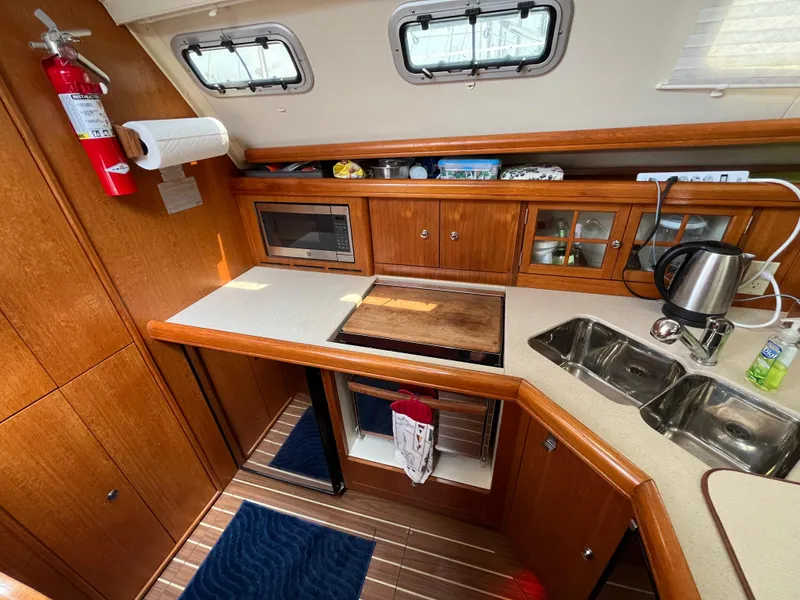 Slide: The Image of 2004 Hunter 41 yacht kitchen with wooden cabinets, microwave, sink, and kettle. - 22