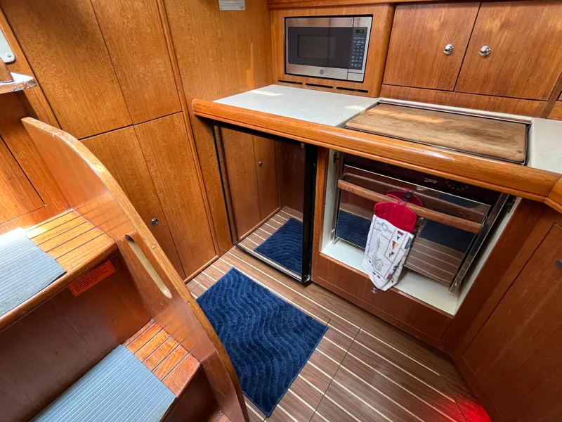 Slide: The Image of 2004 Hunter 41 yacht interior kitchen with wood cabinetry, microwave, and compact appliances. - 23