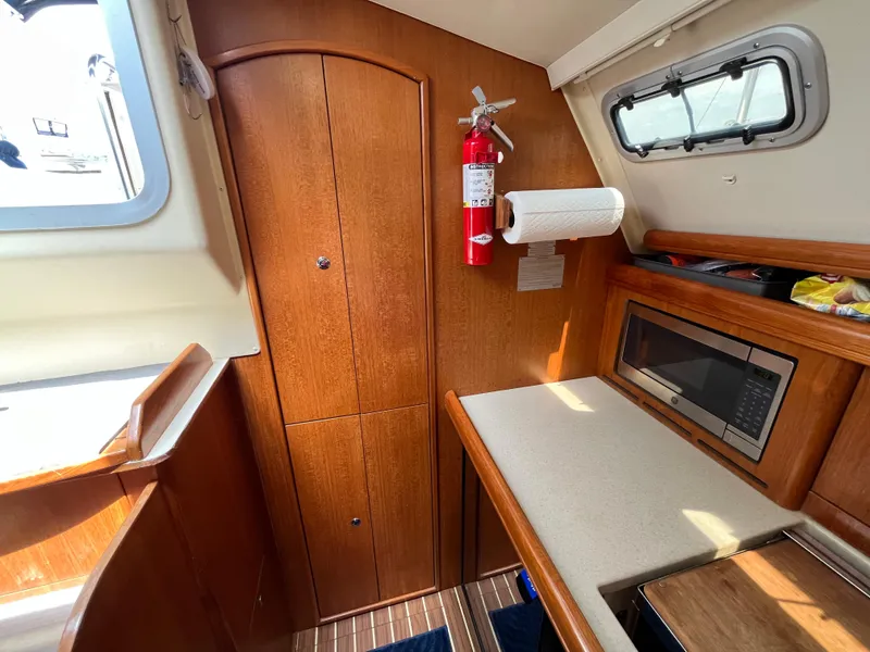 Slide: The Image of Interior of 2004 Hunter 41 sailboat with wood cabinetry, microwave, and fire extinguisher. - 26