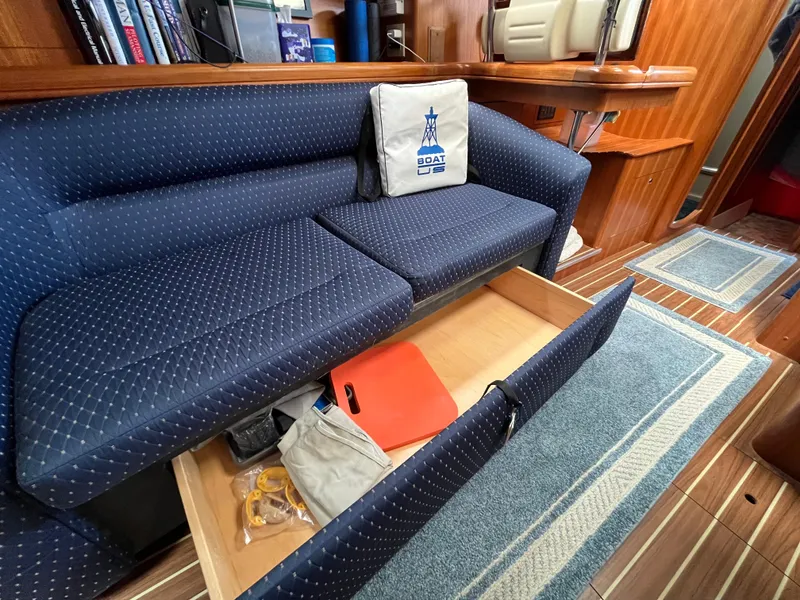 Slide: The Image of 2004 Hunter 41 sailboat interior with blue cushioned seating and storage drawer open. - 40