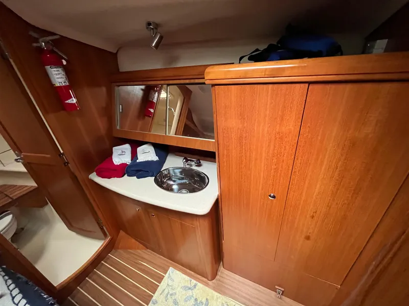 Slide: The Image of Interior of a 2004 Hunter 41 sailboat bathroom with wooden cabinetry and a stainless steel sink. - 42