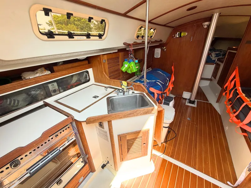Slide: The Image of Interior of 1991 Tartan Thomas 35 sailboat with wooden flooring and compact kitchen area. - 18
