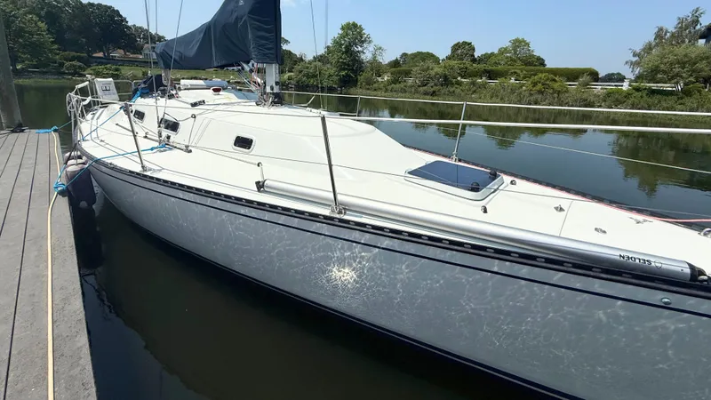 Slide: The Image of Sailboat Tartan Thomas 35, 1991 model, docked on a calm river. - 2