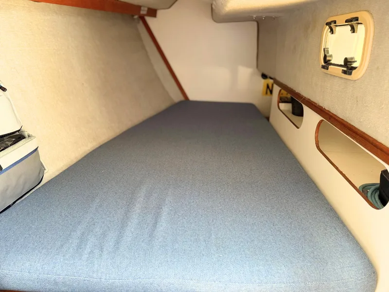 Slide: The Image of Interior cabin of 1991 Tartan Thomas 35 sailboat with blue mattress and porthole. - 24
