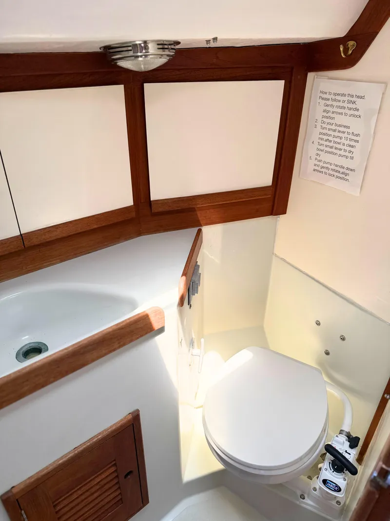 Slide: The Image of 1991 Tartan Thomas 35 yacht bathroom with toilet and sink, featuring wooden accents. - 27