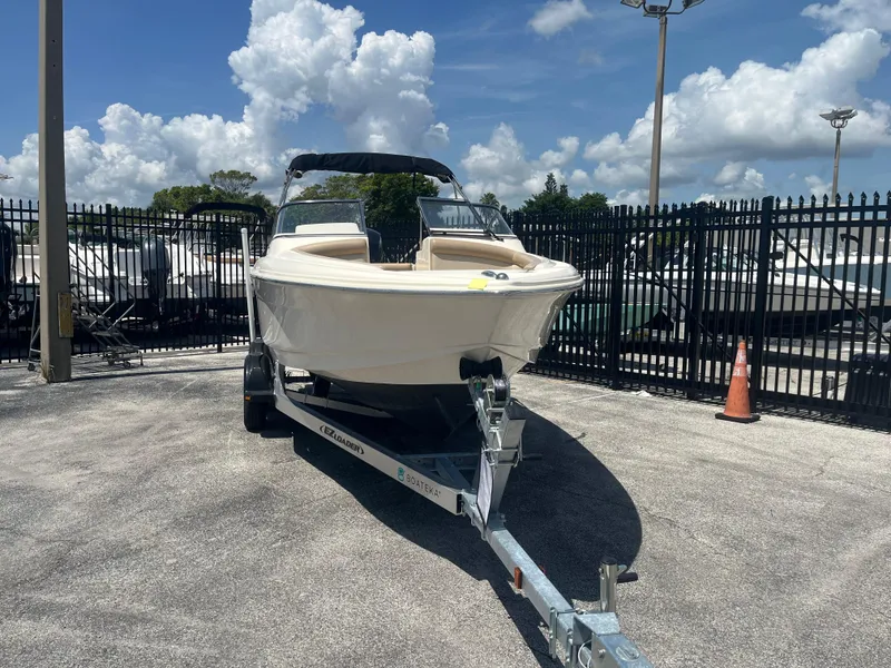 Slide: The Image of 2022 Scout 210 Dorado boat on trailer, parked outdoors under a clear sky. - 2