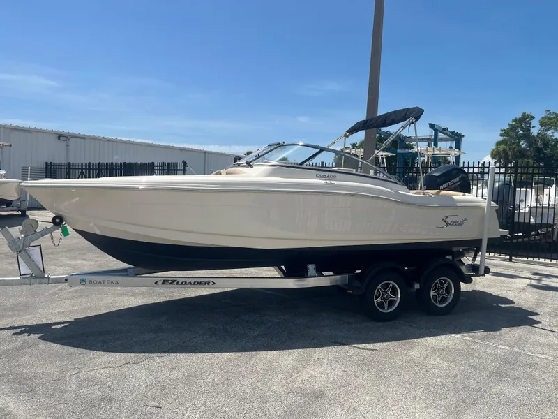 Slide: The Image of 2022 Scout 210 Dorado boat on trailer, parked outdoors under clear blue sky. - 4