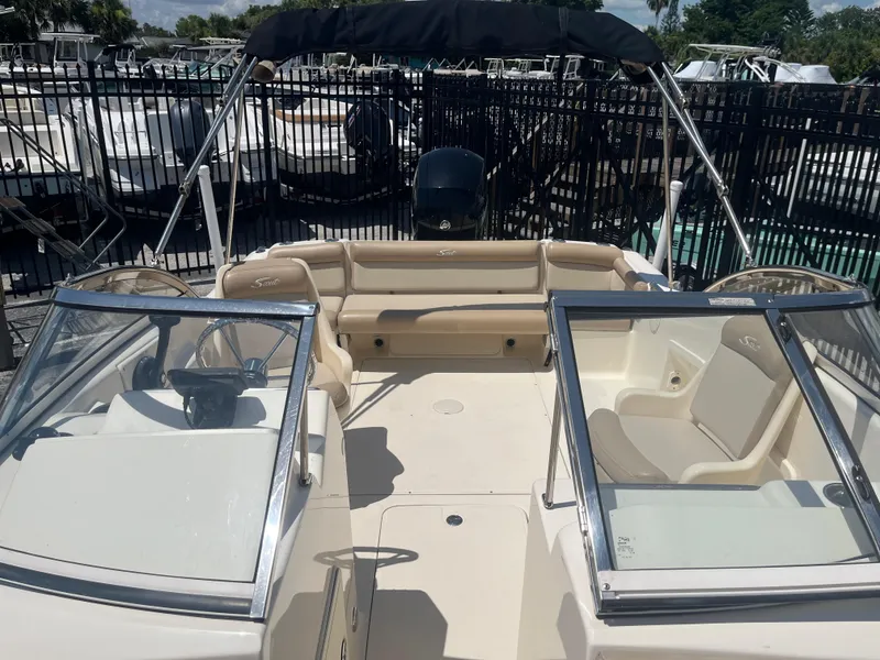 Slide: The Image of 2022 Scout 210 Dorado boat interior with seating and steering wheel, docked outdoors. - 6