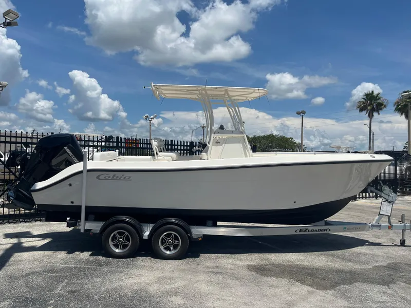 The Image of 2021 Cobia 237 Center Console boat on trailer under blue sky. - 0