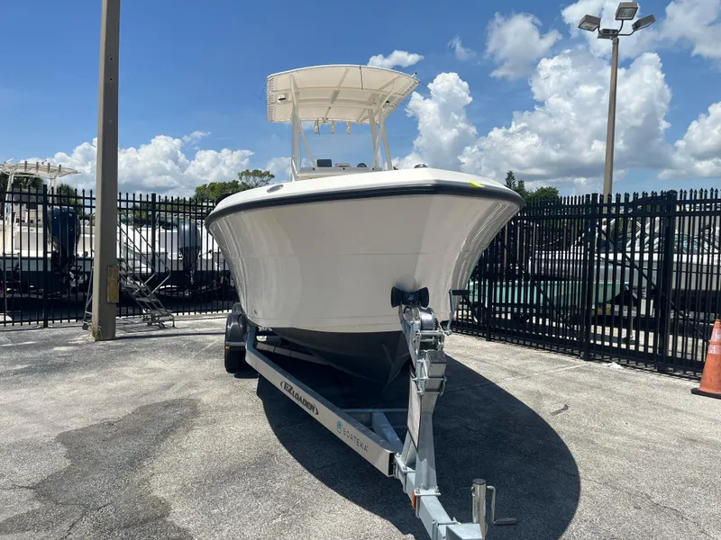 Slide: The Image of 2021 Cobia 237 Center Console boat on trailer, parked outdoors under a clear sky. - 2