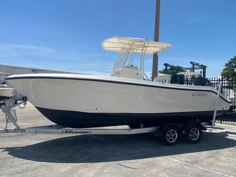 Slide: The Image of 2021 Cobia 237 Center Console boat on trailer under clear blue sky. - 4