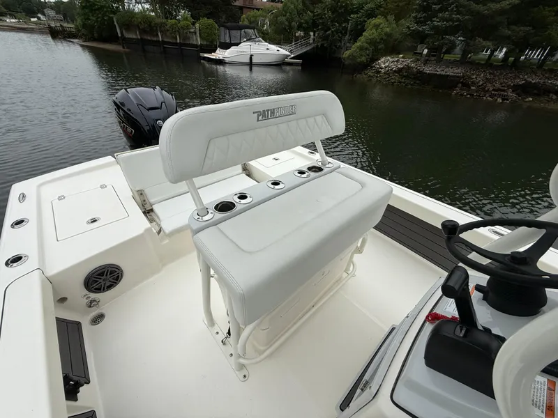 Slide: The Image of 2024 Pathfinder 2200 TRS boat interior with seating and steering wheel by the water. - 10
