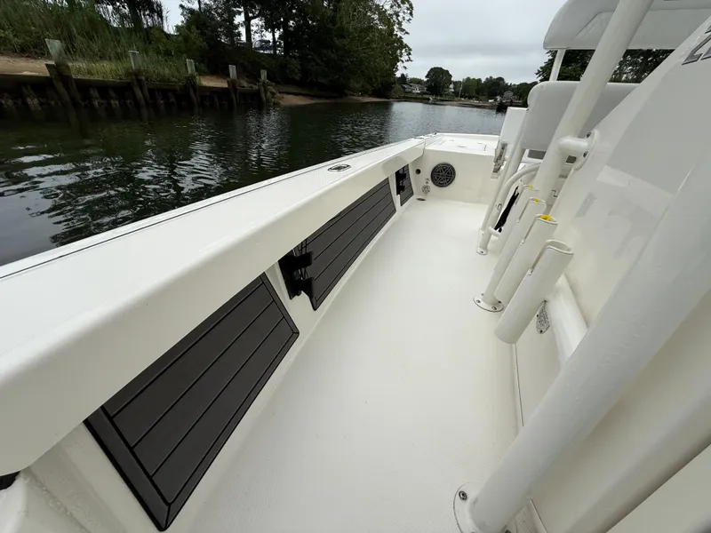 Slide: The Image of 2024 Pathfinder 2200 TRS boat interior, featuring sleek design and rod holders by the water. - 11