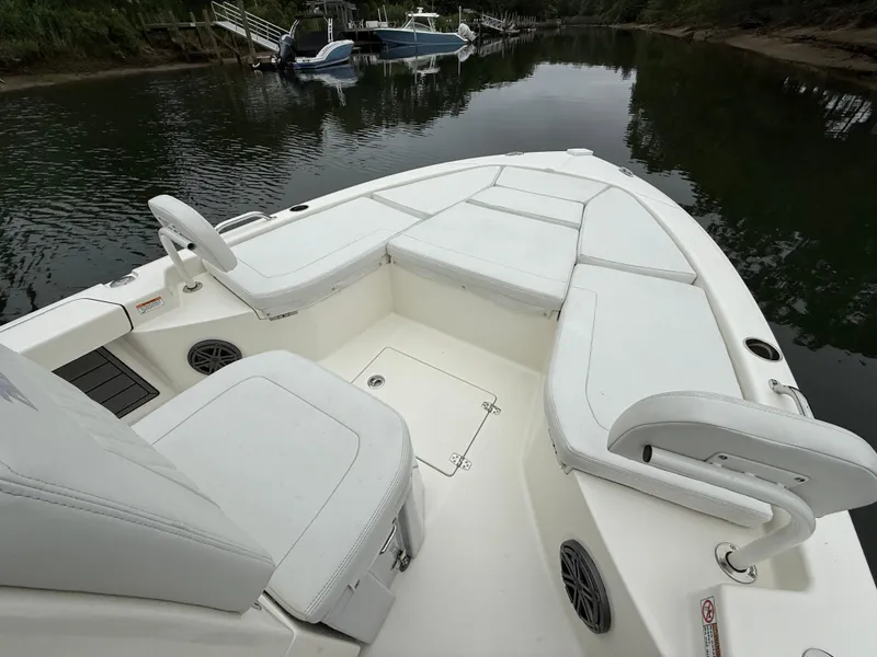 Slide: The Image of 2024 Pathfinder 2200 TRS boat interior with white seating, docked on calm water. - 16