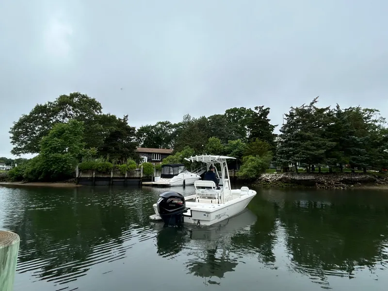 Slide: The Image of 2024 Pathfinder 2200 TRS boat on calm water near lush greenery. - 3