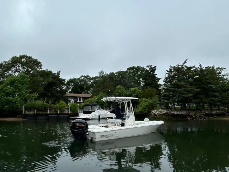 Slide: The Image of 2024 Pathfinder 2200 TRS boat on a calm lake near lush greenery. - 4