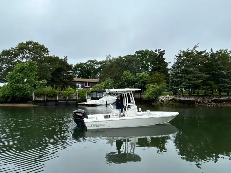 Slide: The Image of 2024 Pathfinder 2200 TRS boat cruising on a calm river near lush greenery. - 5