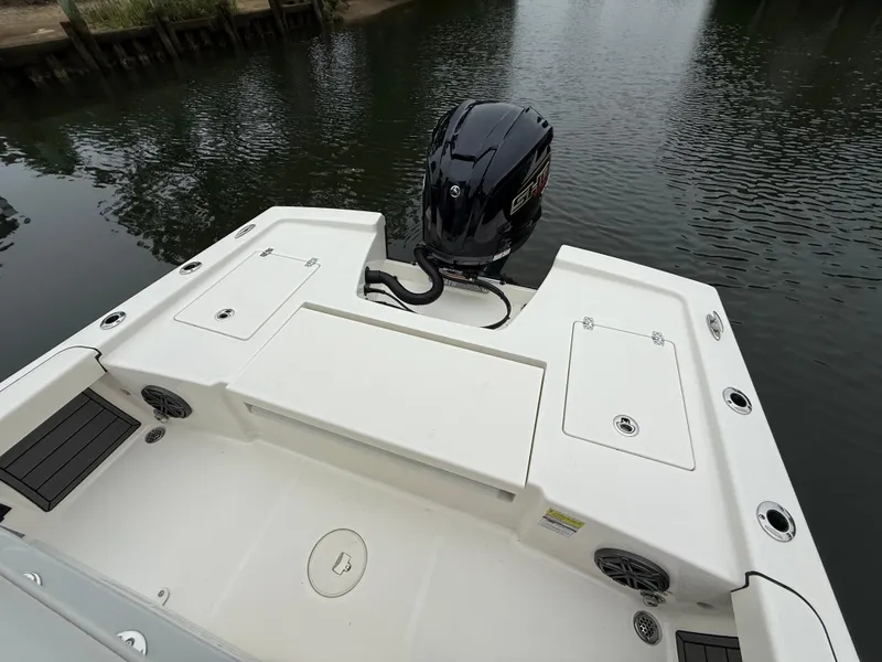 Slide: The Image of 2024 Pathfinder 2200 TRS boat stern with motor, docked on calm water. - 8