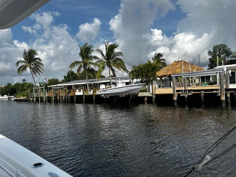The Image of 2023 Everglades 243 Center Console boat docked by palm trees and waterfront homes. - 1