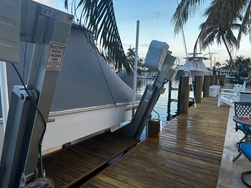 Slide: The Image of Docked 2023 Everglades 243 Center Console boat with cover, near palm trees and water. - 15