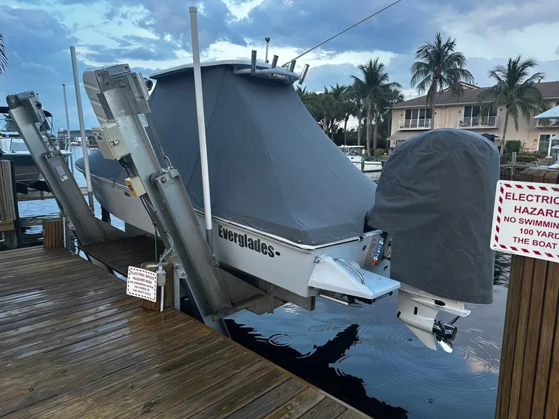 Slide: The Image of 2023 Everglades 243 Center Console boat docked, covered, with electric hazard warning sign. - 17