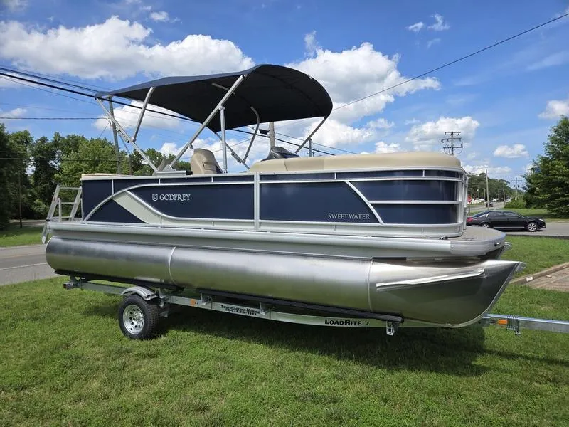 The Image of 2025 Godfrey Sweetwater 2086 FS Sport Tube pontoon boat on trailer, parked on grass. - 1