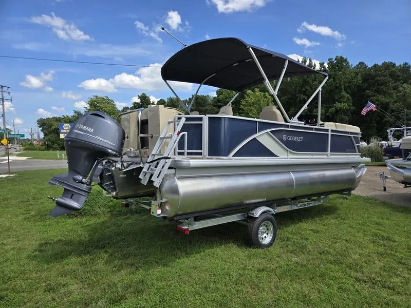 Slide: The Image of 2025 Godfrey Sweetwater 2086 FS Sport Tube pontoon boat on trailer, parked on grass. - 2