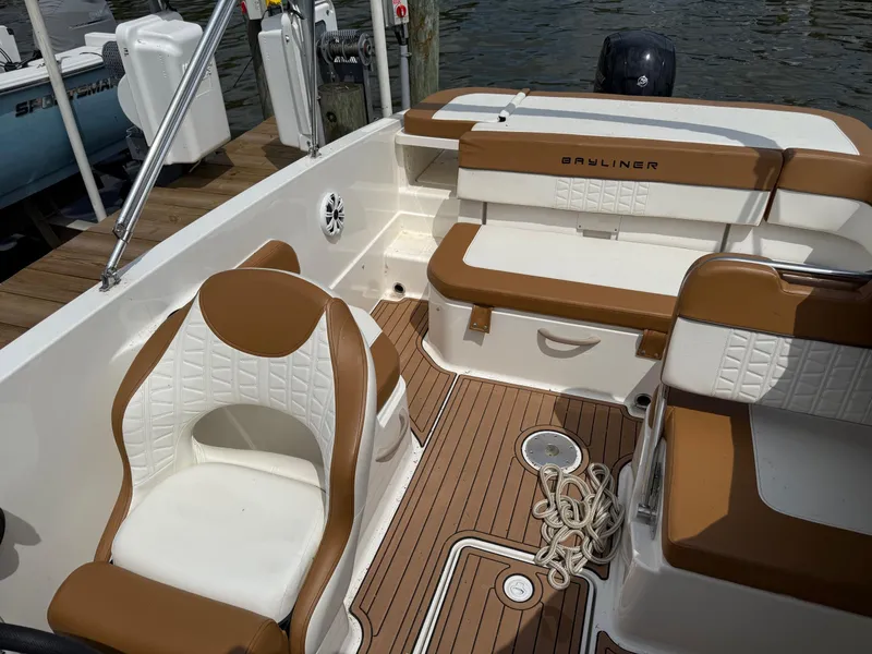 Slide: The Image of 2021 Bayliner VR6 Bowrider OB interior with brown and white seating, docked by the water. - 24
