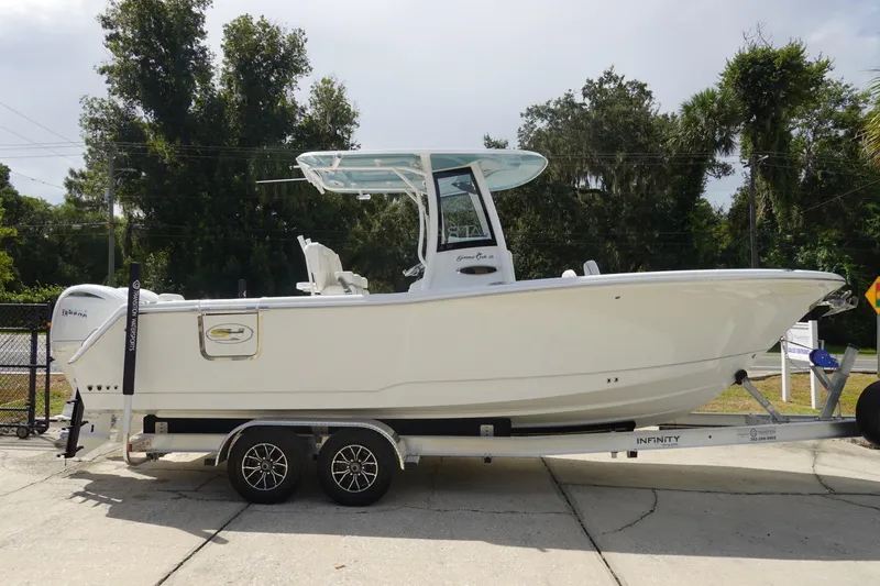 Slide: The Image of 2026 Sea Hunt Gamefish 25 boat on trailer, parked outdoors with trees in background. - 5