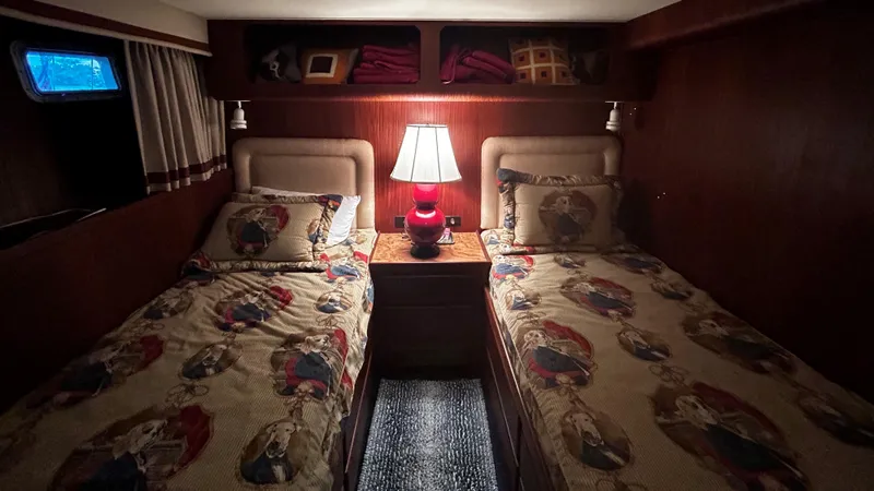 Slide: The Image of Cozy twin bedroom on 1987 Hatteras 58 Motor Yacht with nautical-themed bedding and warm lighting. - 10
