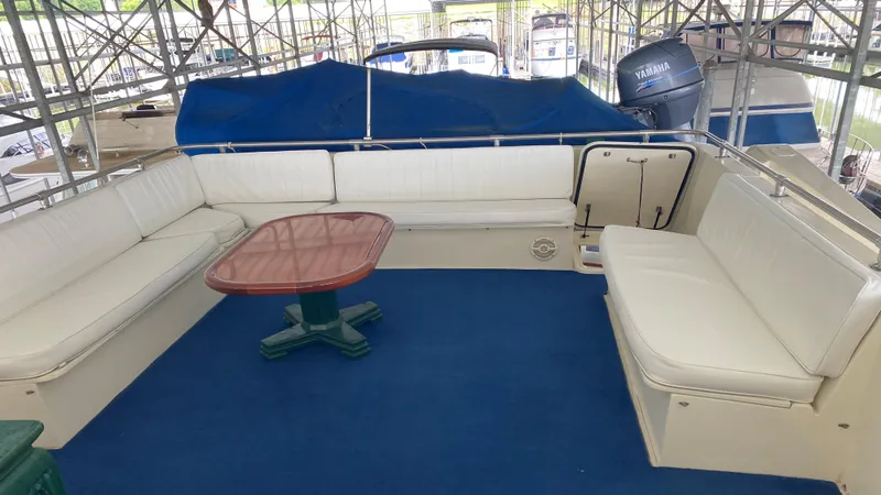 Slide: The Image of 1987 Hatteras 58 Motor Yacht interior with white seating and wooden table on blue carpet. - 17