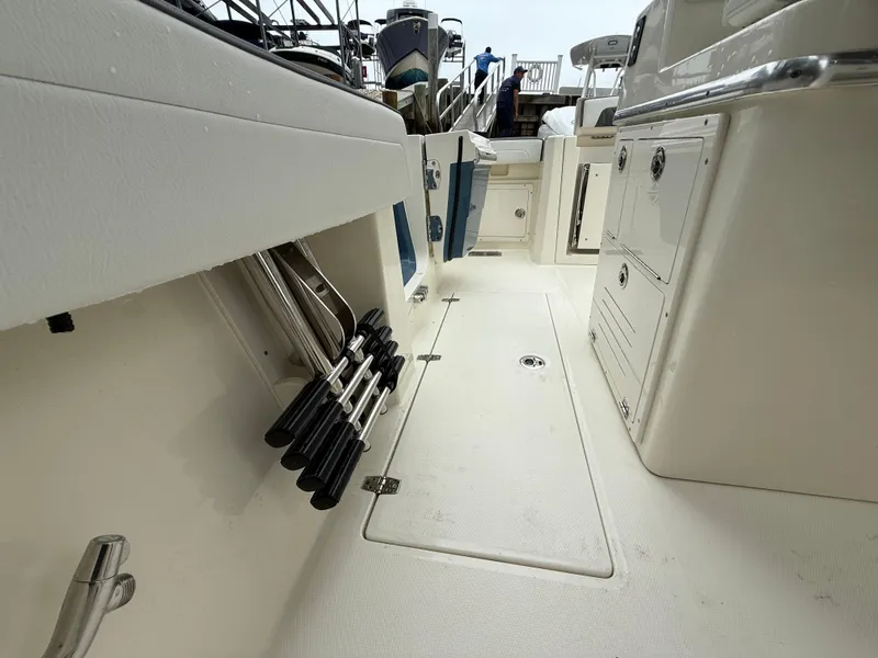 Slide: The Image of 2025 Cobia 265 Open Center Console boat interior with storage compartments and rod holders. - 13