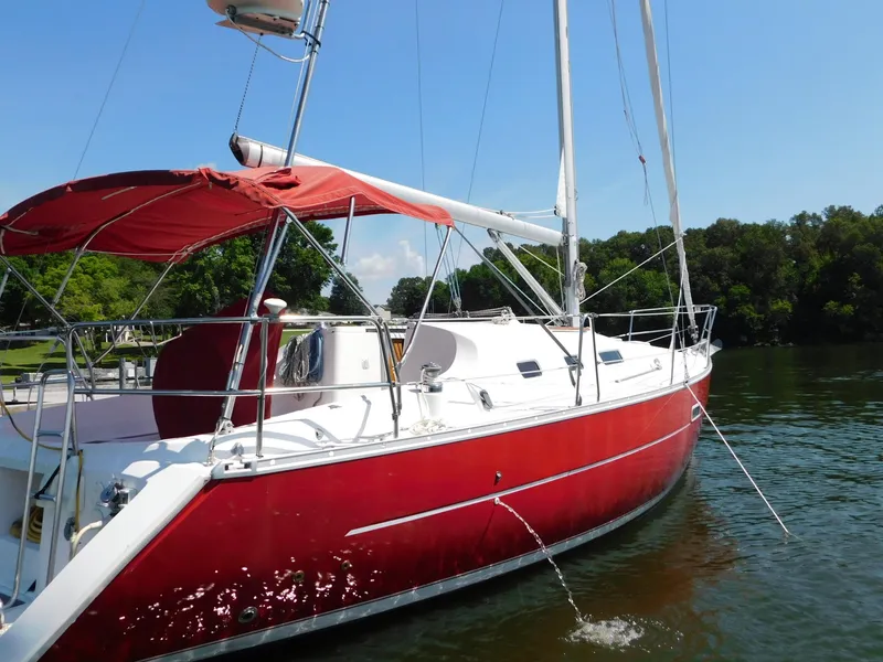 Slide: The Image of 2005 Beneteau Oceanis Clipper 323 sailboat with red hull and canopy on calm water. - 11