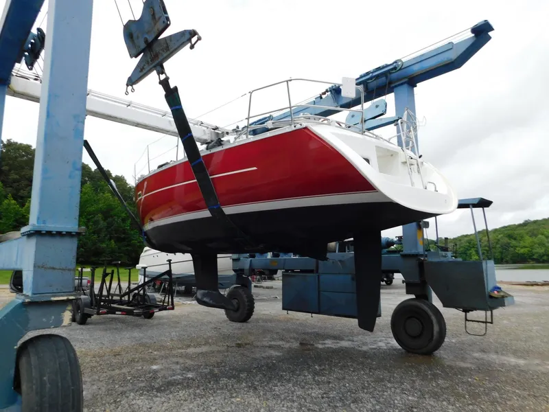 Slide: The Image of 2005 Beneteau Oceanis Clipper 323 sailboat in dry dock, red hull, being lifted by crane. - 12