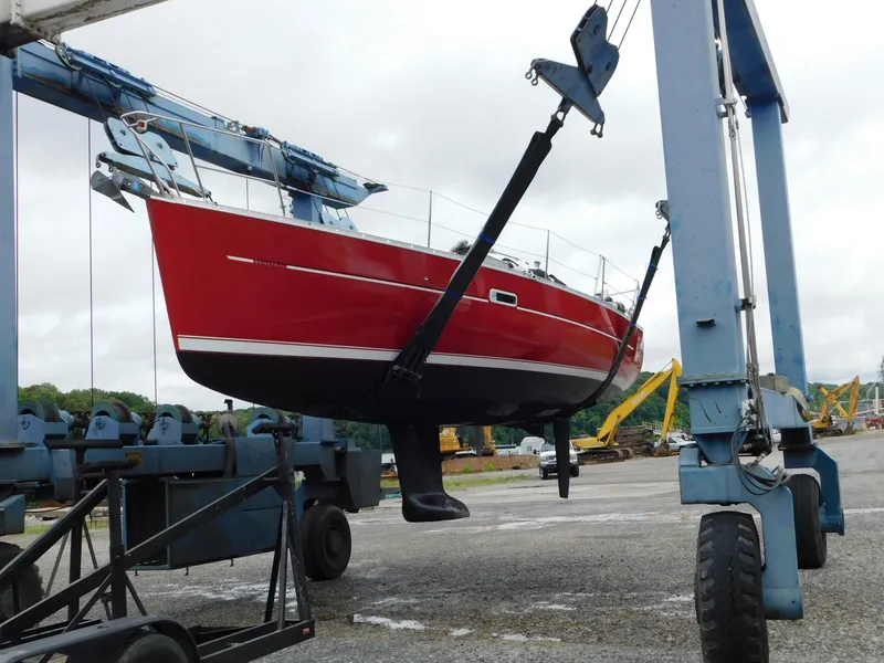 Slide: The Image of Red 2005 Beneteau Oceanis Clipper 323 sailboat lifted by crane in shipyard. - 13