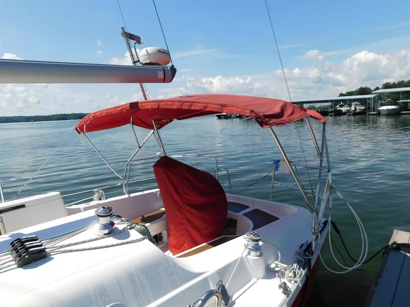 Slide: The Image of 2005 Beneteau Oceanis Clipper 323 sailboat with red canopy docked on calm water. - 22