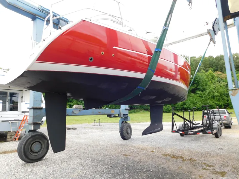 Slide: The Image of Red 2005 Beneteau Oceanis Clipper 323 sailboat lifted by crane, showing hull and keel. - 3