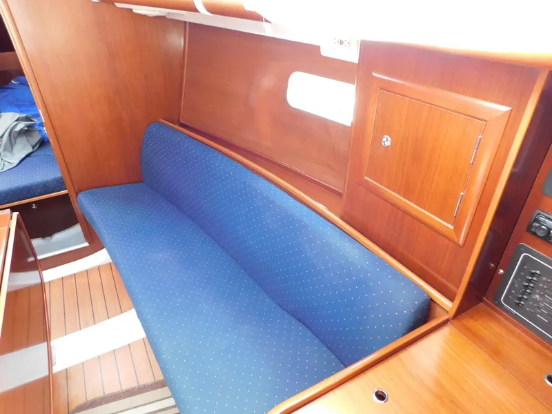 Slide: The Image of Interior of 2005 Beneteau Oceanis Clipper 323 with blue cushioned seating and wooden cabinetry. - 31