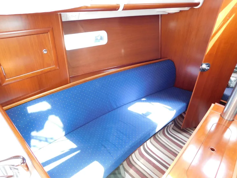 Slide: The Image of Interior of 2005 Beneteau Oceanis Clipper 323 with blue cushioned seating and wooden cabinetry. - 32