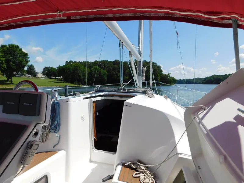 Slide: The Image of 2005 Beneteau Oceanis Clipper 323 sailboat on a serene lake with lush greenery. - 42