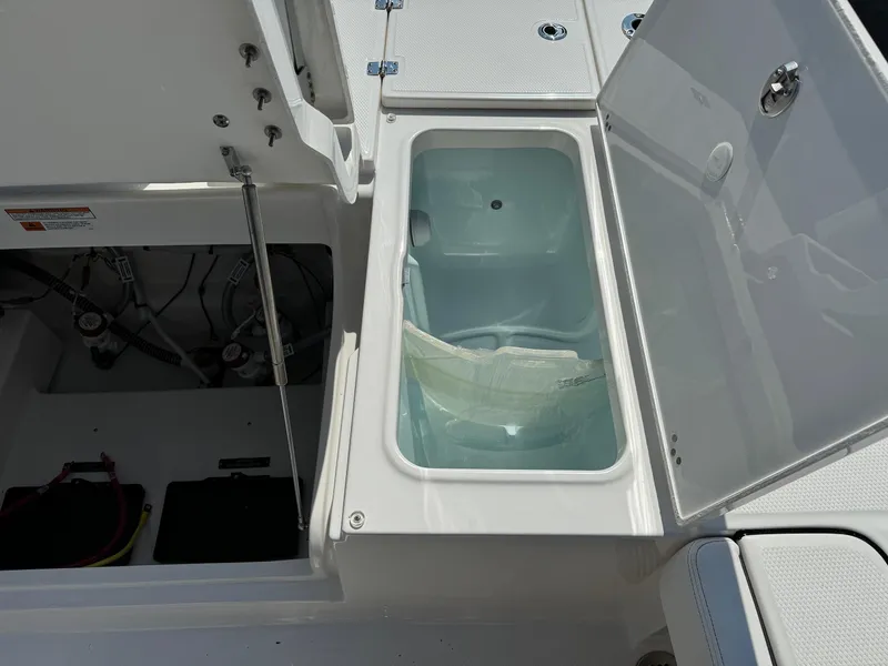Slide: The Image of 2025 Robalo R246 CAYMAN boat storage compartment with open lid, showcasing interior details. - 15