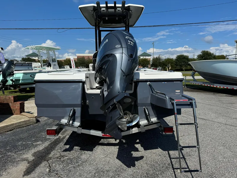 Slide: The Image of 2025 Robalo R246 CAYMAN boat with Yamaha outboard motor and ladder, parked outdoors. - 2