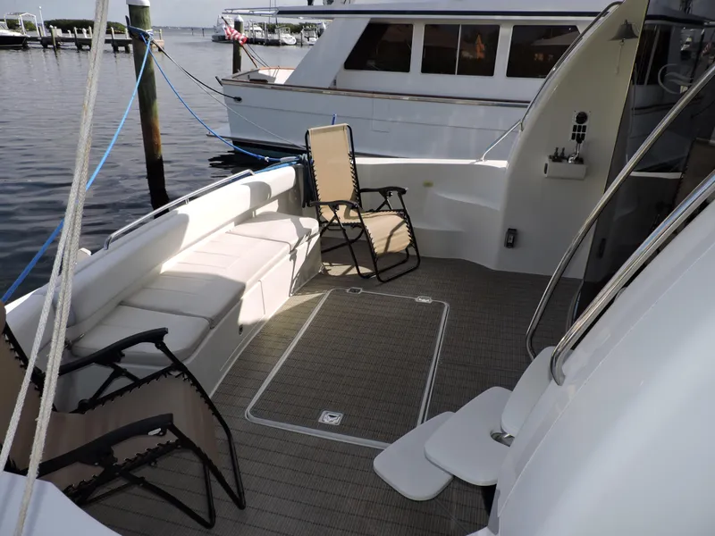 Slide: The Image of 2010 Carver 56 Voyager SE yacht deck with seating and chairs, docked at marina. - 2